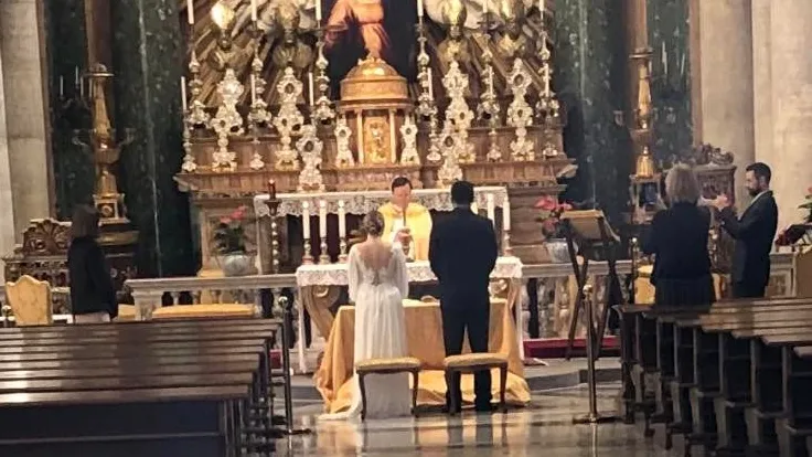 In una chiesa vuota a Roma, due giovani hanno celebrato il loro matrimonio in intimità, con la sola presenza di un prete e due testimoni. La sposa, in dolce attesa, ha aggiunto un tocco emotivo alla semplice cerimonia.